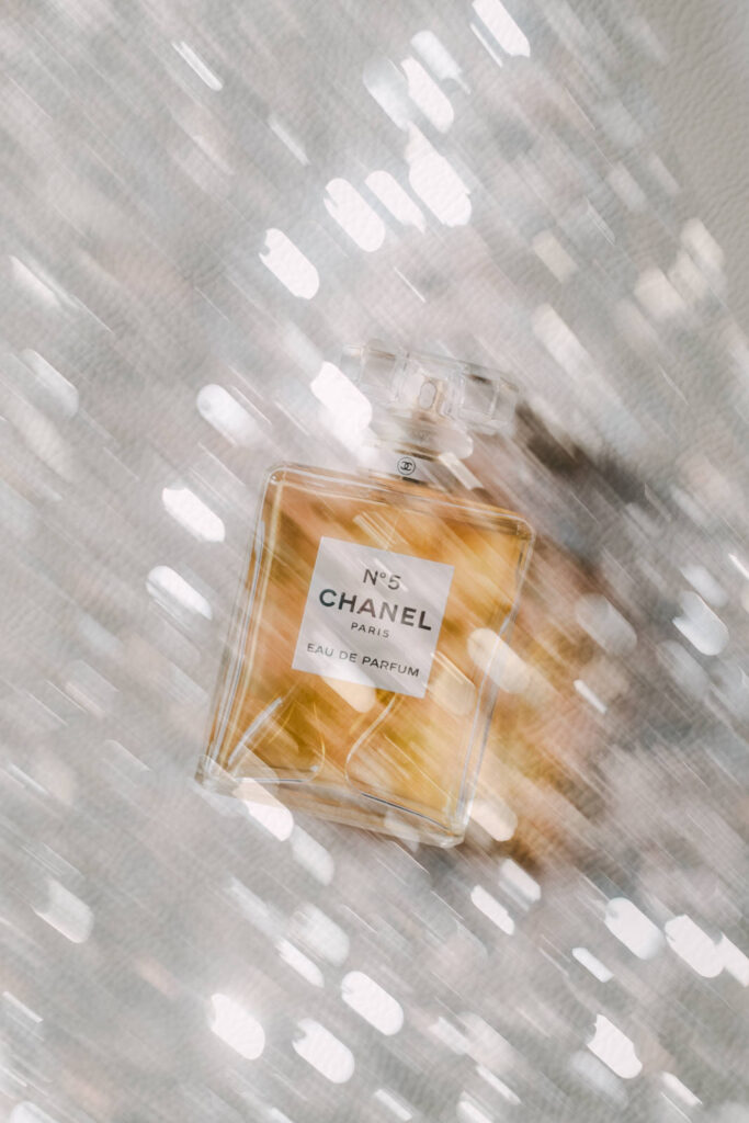 Luxury bridal details flatlay with Chanel perfume, pearl necklace and white flowers for a destination wedding in Provence, south of France