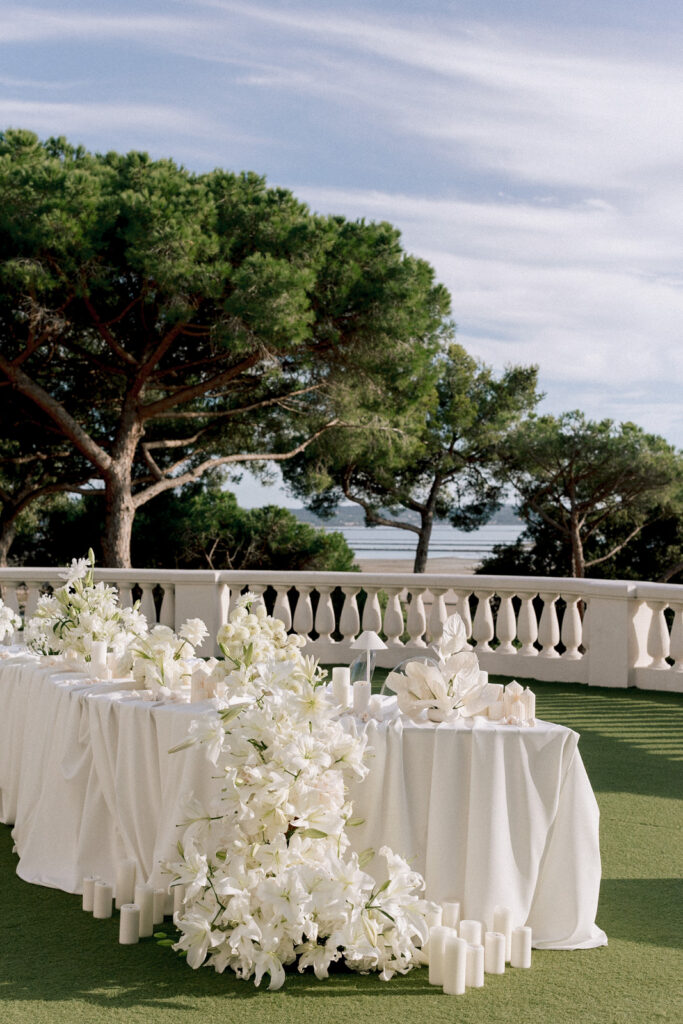 Elegant wedding dinner table decorated with white flowers and candles on a terrace with sea view on the French Riviera, south of France