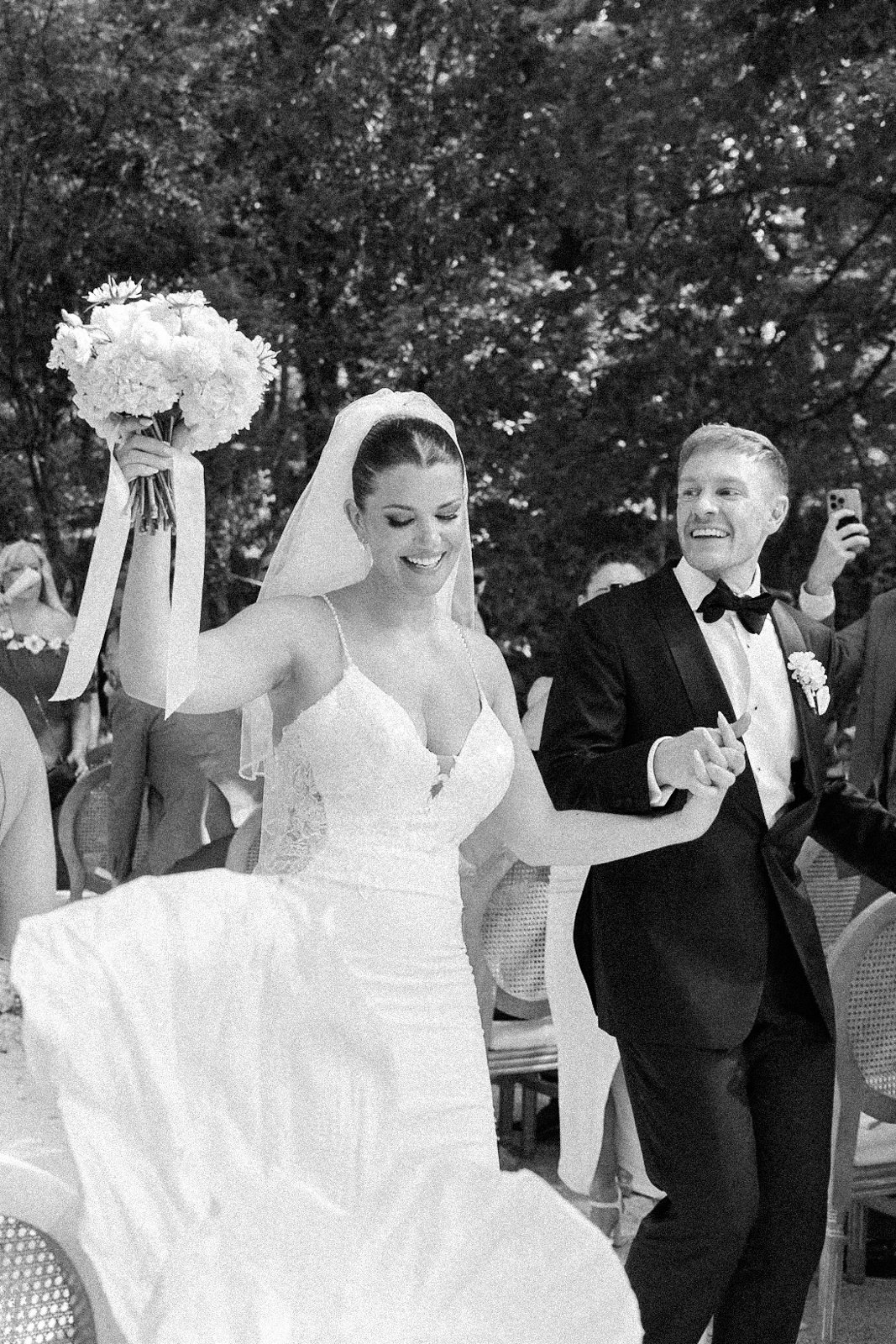 Joyful bride and groom exiting the wedding ceremony with the bride holding her bouquet up at a venue in Provence, south of France