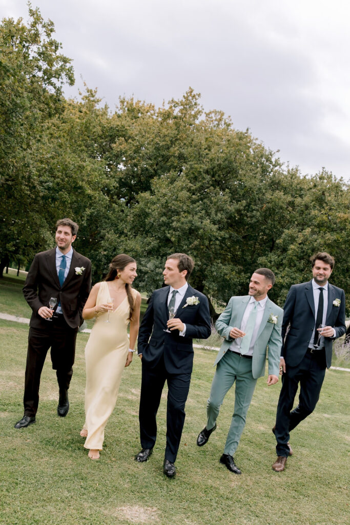 Groomsmen and wedding party walking with champagne glasses at a destination wedding in Provence, south of France