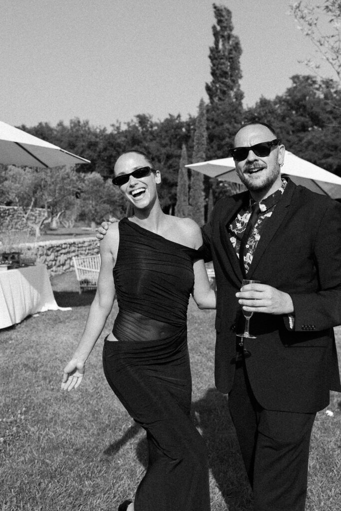Black and white candid of guests laughing with cypress trees during a wedding reception in Provence, south of France