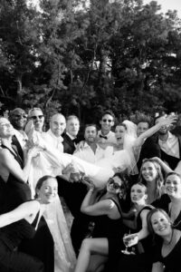 Black and white photo of the bride lifted by guests during the wedding party in Provence, south of France